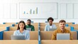© SUPERARTMAN - a diverse team of four young professionals working together in a modern office space. The team is seated in a lecture hall style with their laptops in front of them.