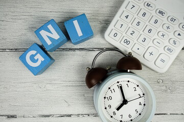 GNI (Gross National Income) text with alarm clock and calculator on wooden background