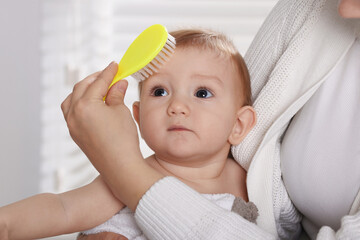 Wall Mural - Woman brushing hair of her little baby indoors, closeup