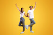 © Prostock-studio - Wow, Yes. Portrait of overjoyed young couple holding hands, excited guy raising hand and shaking clenched fist, lady showing peace sign gesture. Casual cool couple posing, full body length, free space