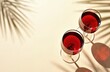 © miss irine - Summer minimal flat lay with two glasses of red wine on beige background. Sunlight and palm leaf shade. Parties events celebration relaxation concept.