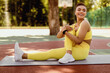 © Prostock-studio - Laughing black woman stretching legs outside. African American female athlete in wireless earbuds training abductor hip flexor muscle in buttocks to relieve sports pain practicing seated spinal twist