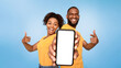 © Prostock-studio - Check this out, cellphone display mockup. Positive African American couple pointing at cellphone with empty screen on blue background, selective focus. Template for mobile app, website or online ad