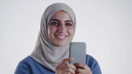 Wall Mural - A full-length shot of a happy Jordanian female star, looking at her phone and wearing a blue shirt on a white background.