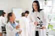 © Pixel-Shot - Teenage girl and teacher holding plant with microscope in Biology class at school