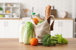 © Pixel-Shot - Grocery bag with different fresh products on wooden table in kitchen