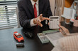 © kamiphotos - a car salesman is explaining the details of a car and the pricer that a buyer is interested in, the showroom sales manager explained the amount of interest