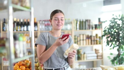 Wall Mural - Young woman buyer scanning qr code for mayonnaise sauce in grocery store