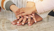 © peopleimages.com - Family, hands stack and united in home, fun activity games and proud of support in relationship. Parents, children and pile for motivation in bonding on kitchen table, connect and celebrate goals