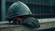 © narak0rn - A construction helmet rests on a wooden surface alongside a pair of work gloves, symbolizing safety and labor in a construction environment.