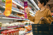 © zhouyilu - Woman Shoppers Exploring Aisles In a Modern Grocery Store