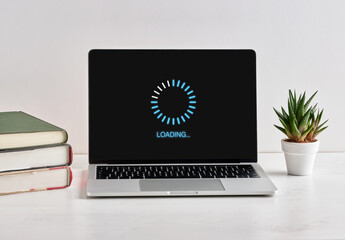laptop showing loading screen with books and plant