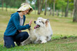 © LeeSensei - An Alaskan Malamute joyfully gives a high-five to a smiling woman in a green hat at a park, highlighting companionship, obedience training, and outdoor happiness