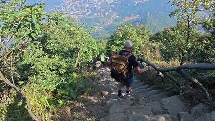 Wall Mural - Caucasian gray-haired hiking man with backpack descends from Wutong Mountain in Shenzhen, China