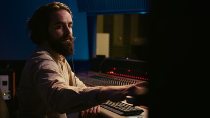 Fototapete - Audio expert operating motorized faders and mixing console in control room, using sliders and switchers buttons to edit and process sounds. Music designer and producer recording tracks. Camera B.