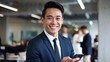 © Milirani - Smiling Asian Businessman Modern Office Professional Happy Successful Entrepreneur Mobile Phone Holding Corporate Worker Smart Casual Attire Positive Attitude Confident Male Executive Business Meeting