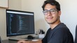 © Sandor - Young hispanic software developer smiling and working at his computer writing code in his home office