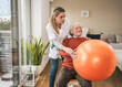 © Westend61 - Home caregiver assisting senior man doing exercise with fitness ball