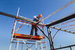 © Westend61 - Mature construction worker installing metal tubes with drill under blue sky