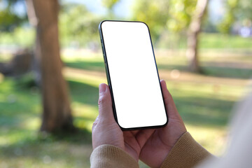 Wall Mural - Mockup image of a woman holding mobile phone with blank white desktop screen in the outdoors