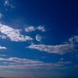 © Joshua Chinedu - A photo of the sky at night with the moon, stars, and clouds. The sky is bright and clear, with a few clouds scattered across the sky. The moon is partially visible, with a portion of its surface cove