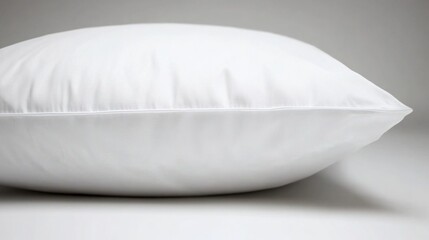 Wall Mural - A single white pillow resting on a plain white table, suitable for use in still life photography or decorative settings