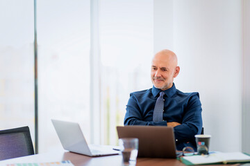 Wall Mural - Businessman sitting at office desk and using his laptop for work