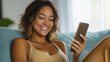 © Andres Mejia - Happy latin woman relaxing on sofa using smartphone at home