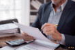 © Tj - Close-up of hands of senior businessman holding and reviewing documents with pen, preparing to sign contract in office, concept of business, finance, and accounting