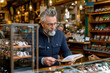 © Degimages - A customer browses stylish eyeglasses on a display, holding a pair while checking