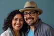 © Markus Schröder - Portrait of a grinning latino couple in their 20s donning a classic fedora while standing against solid color backdrop