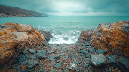 Wall Mural - rocky cove with turquoise ocean waves crashing on shore under a cloudy sky.
