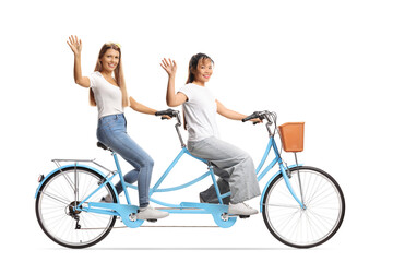 Wall Mural - Young women riding a tandem bicycle and waving