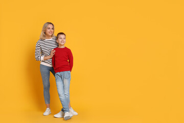 Canvas Print - Happy mother and son on orange background. Space for text