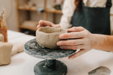 Poster - Process of creating ceramic products. Female potter hands shows ceramic bowl ready for firing in a kiln.
