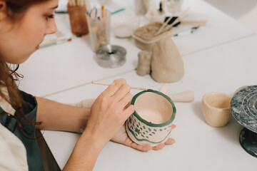Poster - Design earthenware cup with a traditional pattern. Artist is making decoration on the clay ceramic mug after oven firing.