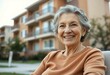 © iushakovsky - Happy elderly woman in front of a residential apartment building