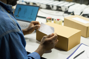 Leinwandbilder - Hands of young male factory worker putting sticker with barcode on cardboard box with new item or equipment