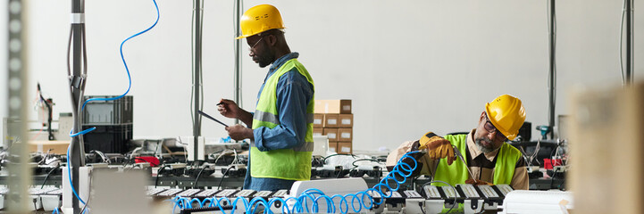 Leinwandbilder - Header of two intercultural male professionals looking through document and taking notes and using electric handtool