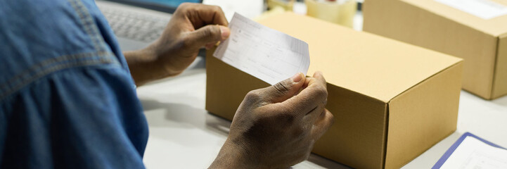 Leinwandbilder - Header of hands of young male factory worker putting sticker with barcode on cardboard box with new item or equipment