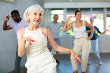 Wall Mural - Group of multinational sports aged people rehearsing modern dance in dance hall