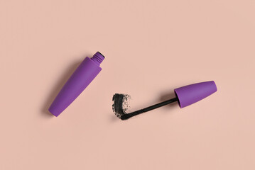 Wall Mural - Black mascara in purple tube with sample on pink background