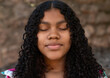 © Martin Stock Studio - Young woman with curly hair closing her eyes and relaxing