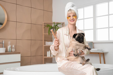 Wall Mural - Young woman with makeup brushes and pug dog in bathroom