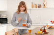 © Pixel-Shot - Young woman with sweet honey and cup of tea in kitchen