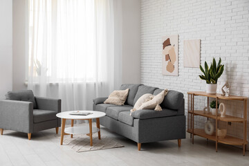 Wall Mural - Comfortable sofa, armchair, coffee table and picture hanging on white brick wall in living room