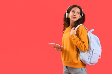 Wall Mural - Female student in headphones with tablet computer on red background