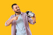 © Pixel-Shot - Young man pointing at VR glasses on yellow background