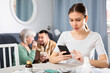 © JackF - Portrait of focused young woman sitting at table with medicines for her sick husband, using phone to make right choice, while her mother-in-law giving drugs to him