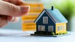 © Stock Photo Memory - Colorful Miniature House Model with Hand Holding Yellow Cards